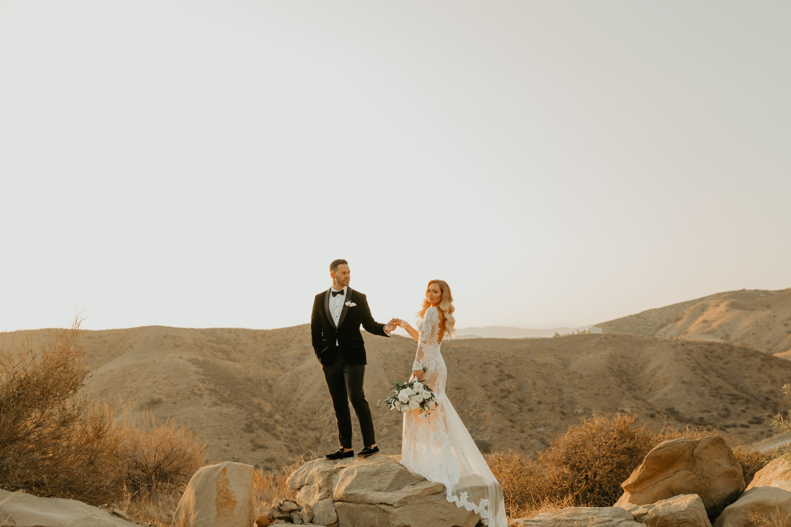 groom holding brides hand on mountain top
