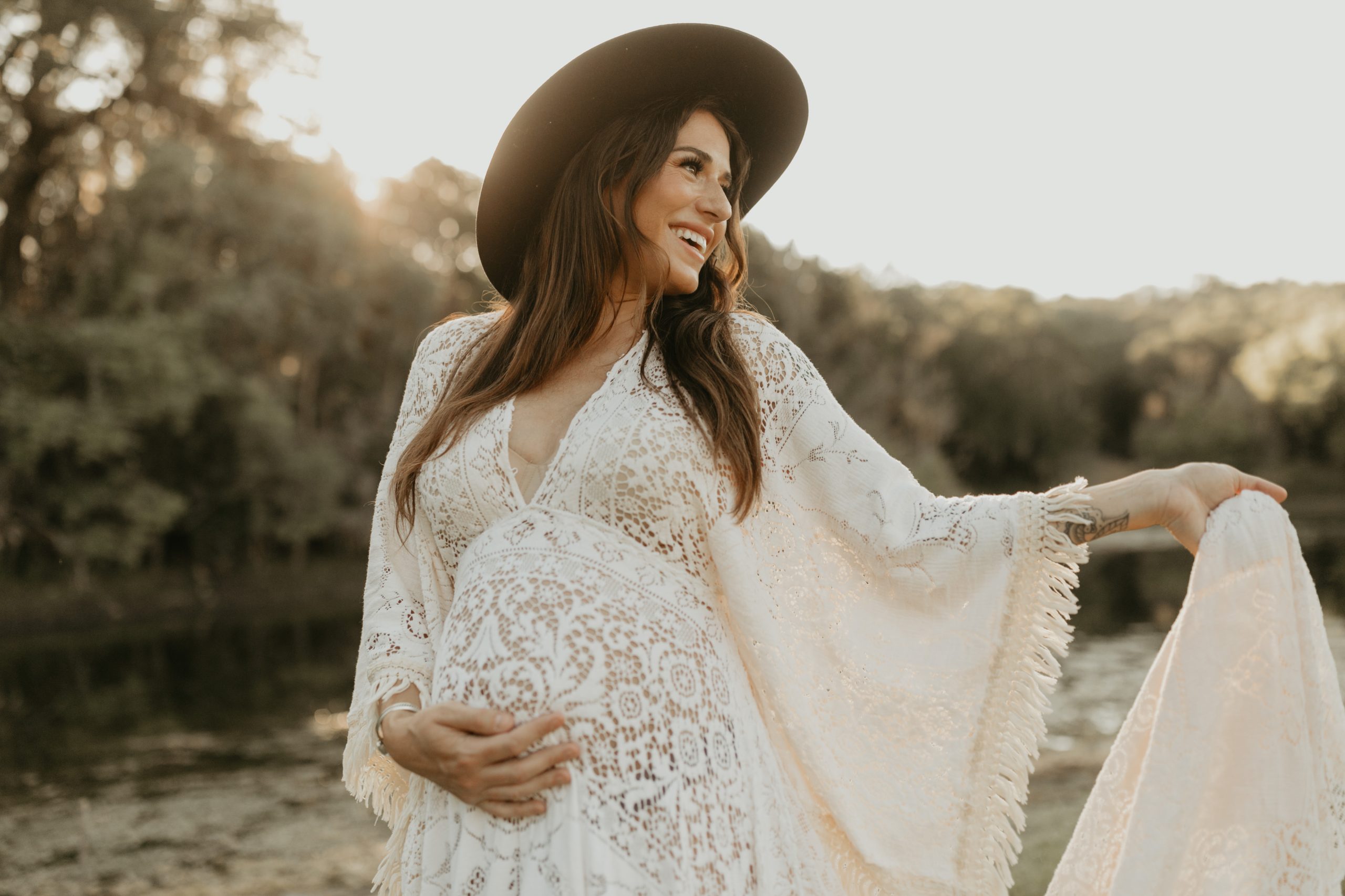 pregnant mom holds belly in beautiful lace dress for maternity photo session