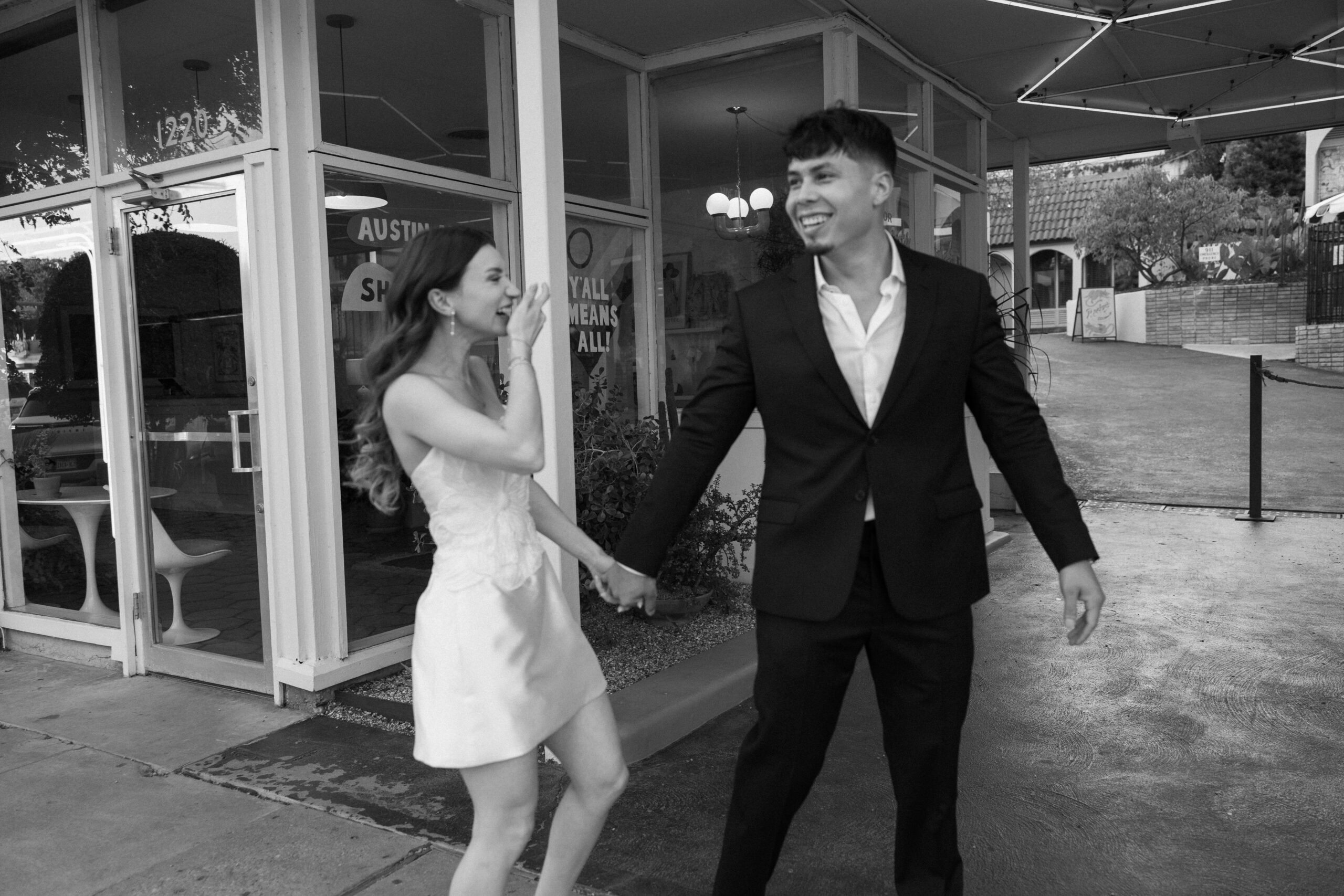 Candid engagement photo of Ana and Pedro laughing together on South Congress Street in Austin, captured by Austin engagement photographer